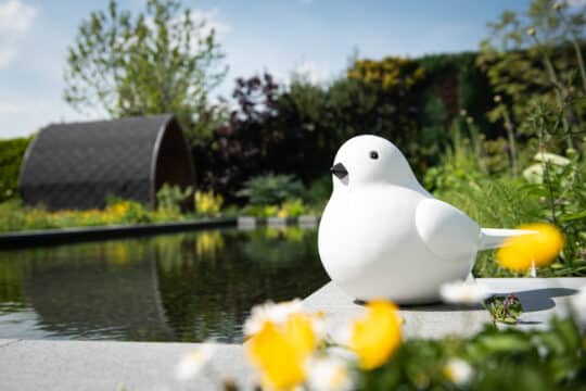modern bird-style garden statue near a pond