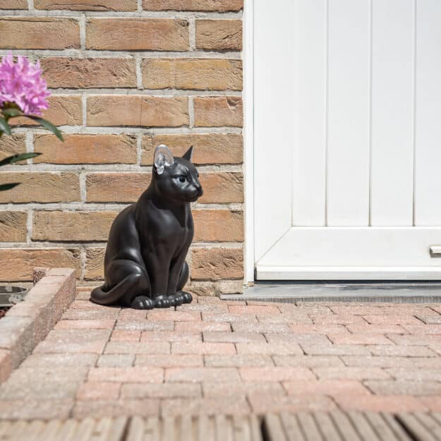 statue jardin style chat moderne noir et oreilles argentées devant porte